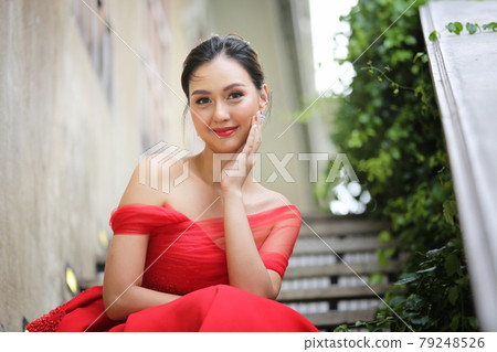Young Asian Woman in a beautiful red dress looking at camera with smile. Fashion model, bride or pre-wedding concept. 79248526