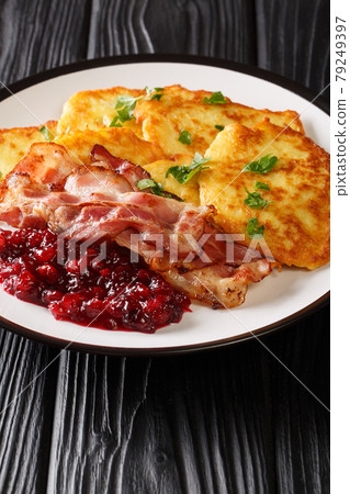 Swedish food potato pancakes with lingonberry jam and bacon close-up in a plate. vertical 79249397