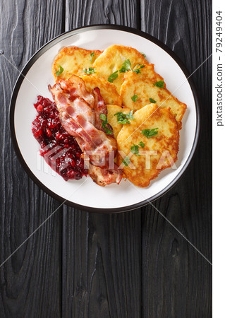 Swedish food potato pancakes with lingonberry jam and bacon close-up in a plate. vertical top view 79249404
