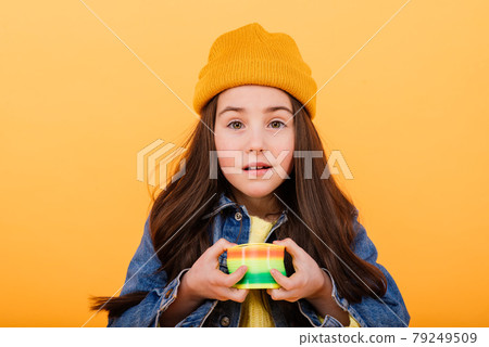 A girl in a multi-colored shirt holds a multi-colored slinky toy in her hands A girl in a multi-colored shirt holds a multi-colored slinky toy in her hands 79249509