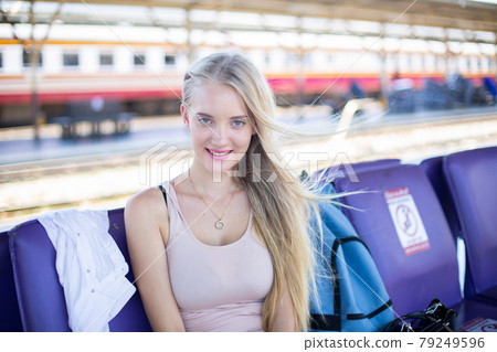 young woman waiting in vintage train, relaxed and carefree at the station platform in Bangkok, Thailand before catching a train. Travel photography. Lifestyle. 79249596