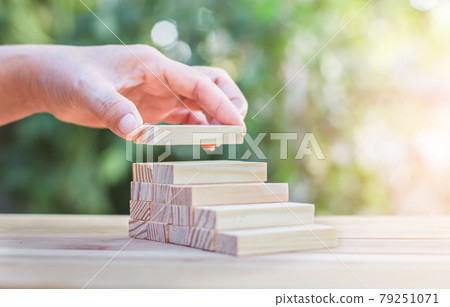Hand arranging wood block stacking as step stair. 79251071
