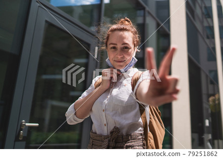 Portrait of young woman taking off face mask outdoors in city, life after covid-19 vaccination. 79251862