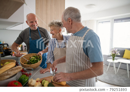 Group of senior friends having party indoors, cooking and talking. Group of senior friends having party indoors, cooking and talking. 79251893