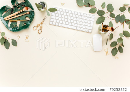 Flat lay home office desk. Female workspace with computer, plate sheet monstera, golden accessories, eucalyptus leaves, on beige background. Top view 79252852