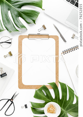 Home office workspace mockup with laptop, tropical leaves Monstera, clipboard, notebook and accessories on white background. Flat lay, top view 79252855