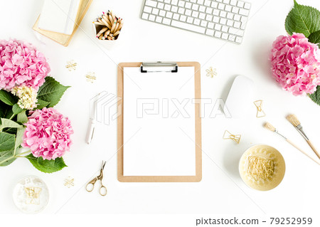 Stylized women's desk. Workspace with clipboard, computer, bouquet hydrangea, accessories on white background. Flat lay. Top view. 79252959