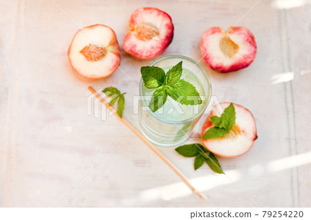 Refreshing iced tea with peppermint and peaches on grey background, selective focus. water drink with peaches 79254220