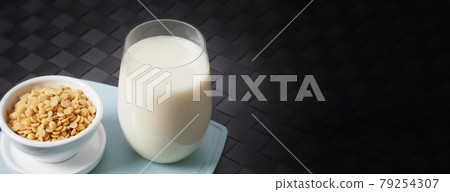 Soy milk with no sugar added in a glass on a green color plastic plate mat. Close-up images of home made healthy soy milk drink and soy beans in small bowl. Black background in a studio shot. Soymilk. Soy milk with no sugar added in a glass on a green color plastic plate mat. Close-up images of home made healthy soy milk drink and soy beans in small bowl. Black background in a studio shot. Soymilk. 79254307