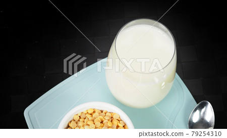 Soy milk with no sugar added in a glass on a green color plastic plate mat. Close-up images of home made healthy soy milk drink and soy beans in small bowl. Black background in a studio shot. Soymilk. Soy milk with no sugar added in a glass on a green color plastic plate mat. Close-up images of home made healthy soy milk drink and soy beans in small bowl. Black background in a studio shot. Soymilk. 79254310