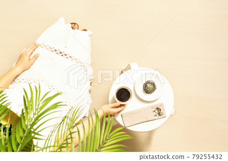 Woman on the beach drinking hot coffee with chocolate cake sitting under palm trees at table and enjoying during exotic summer vacation. Outdoors cafe. Top view 79255432