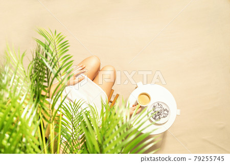 Woman drinking hot coffee with chocolate cookies sitting under palm trees at table. Female on the beach enjoying exotic summer vacation. Outdoors cafe. Top view 79255745