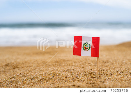 Flag of Peru in the form of a toothpick in the sand of beach opposite sea wave. Travel concept Flag of Peru in the form of a toothpick in the sand of beach opposite sea wave. Travel concept 79255756