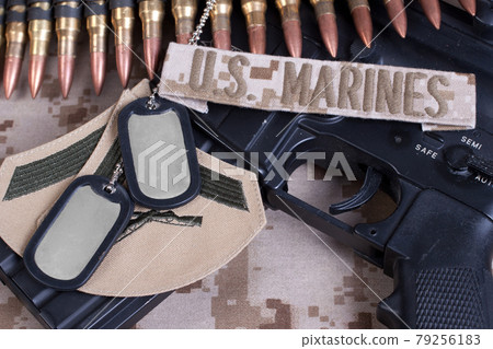 US MARINES branch tape with dog tags, ammunition belt and rifle on desert camouflage uniform US MARINES branch tape with dog tags, ammunition belt and rifle on desert camouflage uniform 79256183