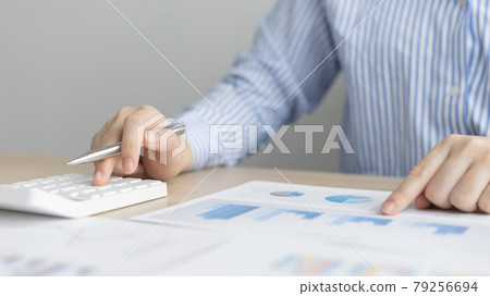 Young Asian businesswoman presses a calculator to calculate income tax and corporate income in a private office, Finance, Accounting, Tex, Statistical graphs of marketers investing in real estate. 79256694