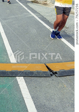 Black and yellow heavy plastic covers for people and vehicle to cross over cables laid on road. Pavement pads to protect electrical wiring on sidewalk in public park. Channel for laying the wires. Black and yellow heavy plastic covers for people and vehicle to cross over cables laid on road. Pavement pads to protect electrical wiring on sidewalk in public park. Channel for laying the wires. 79257256