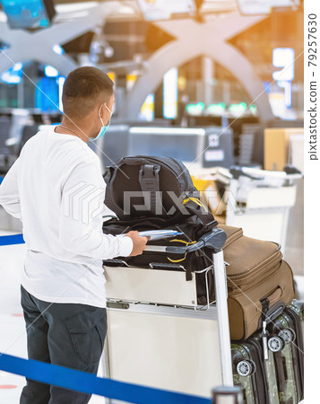 Back view of airline passenger wear face mask to prevent Corona virus (Covid-19) wait to check in counter in airport with staff wear face mask. New normal concept of travel after Covid-19 pandemic. 79257630