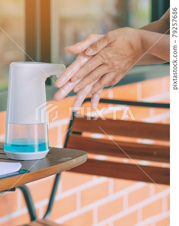 Automatic alcohol dispenser for cleaning hand to prevent the spreading of Coronavirus (Covid-19) on table before entrance to cafeteria. Healthcare concept. New normal lifestyle. Selective focus Automatic alcohol dispenser for cleaning hand to prevent the spreading of Coronavirus (Covid-19) on table before entrance to cafeteria. Healthcare concept. New normal lifestyle. Selective focus 79257686