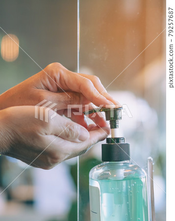 Hands of senior woman pressed blue alcohol gel bottle to prevent the spreading of the Coronavirus (Covid-19) before entrance to cafeteria. Healthcare concept. New normal lifestyle. Selective focus Hands of senior woman pressed blue alcohol gel bottle to prevent the spreading of the Coronavirus (Covid-19) before entrance to cafeteria. Healthcare concept. New normal lifestyle. Selective focus 79257687