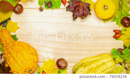 Halloween concept. Autumn Natural harvest with orange pumpkin, fall dried leaves, red berries and acorns, chestnuts on wooden background in shape frame. Beauty Holiday autumn festival concept. 79258226