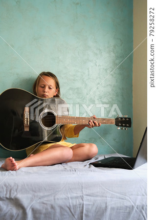 a little girl is learning to play the guitar a little girl is learning to play the guitar 79258272