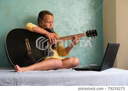 a little girl is learning to play the guitar a little girl is learning to play the guitar 79258273
