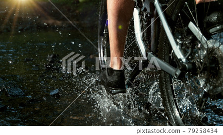 Close-up of mountain rider splashing water in river Close-up of mountain rider splashing water in river 79258434