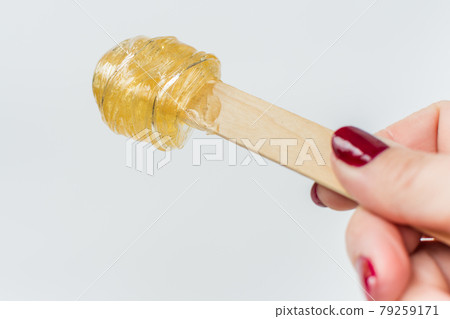 A master stir the sugar paste before removing unwanted hair. Sugaring. Depilation. Epilation. A master stir the sugar paste before removing unwanted hair. Sugaring. Depilation. Epilation. 79259171