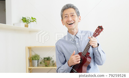 Senior man playing the ukulele at home Senior man playing the ukulele at home 79259526