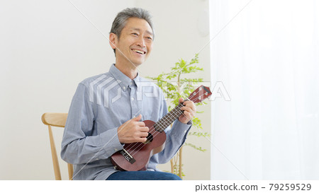 Senior man playing the ukulele at home Senior man playing the ukulele at home 79259529