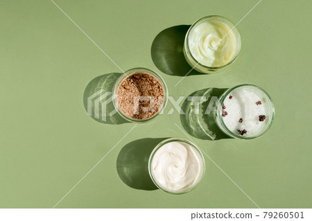 Body treatment and spa concept. Scrub, mask, cream and natural oil cosmetics on green background. Womans cosmetic procedures 79260501