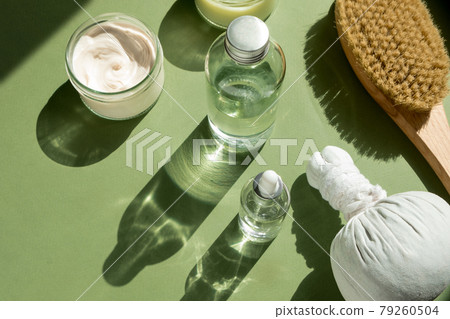 Body treatment and spa concept. Scrub, mask, cream and natural oil cosmetics on green background. Cellulite treatment, dry brushing. Womans cosmetic procedures Body treatment and spa concept. Scrub, mask, cream and natural oil cosmetics on green background. Cellulite treatment, dry brushing. Womans cosmetic procedures 79260504
