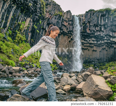 Iceland. Hiker enjoying majestic Svartifoss waterfall. Female is visiting famous tourist attraction of Iceland. Spectacular natural landmark on vacation in Skaftafell. Icelandic nature landscape Iceland. Hiker enjoying majestic Svartifoss waterfall. Female is visiting famous tourist attraction of Iceland. Spectacular natural landmark on vacation in Skaftafell. Icelandic nature landscape 79261231