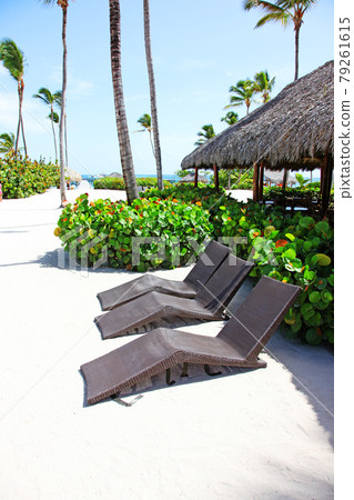 Relax on tropical beach in the sun on deck chairs under umbrella. Relax on tropical beach in the sun on deck chairs under umbrella. 79261615