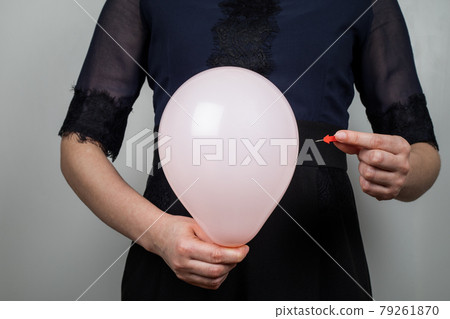 Orange balloon and needle in a woman's hand. Bloated stomach 79261870