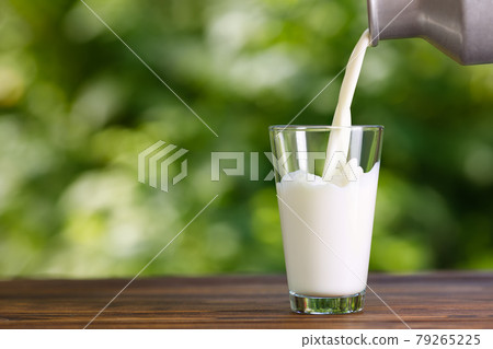 milk pouring from metal can into glass 79265225