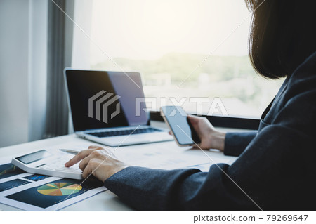 Businesswomen bookkeeper hand use calculator and laptop doing account for paying tax on white desk in working office Businesswomen bookkeeper hand use calculator and laptop doing account for paying tax on white desk in working office 79269647