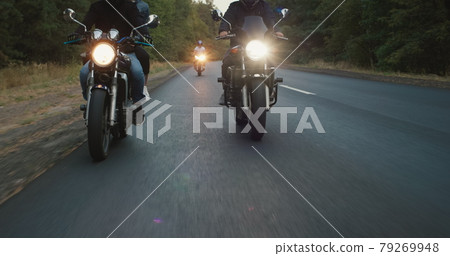 A group of bikers drives along the highway, in the frame you can see the wheels and headlights 79269948