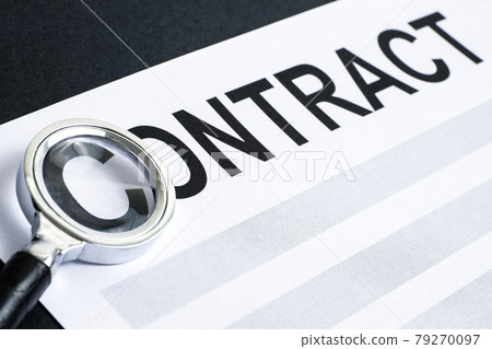 Concept of review and verification of the draft contract. The word "Contract" printed on white paper under a magnifying glass on a black background. 79270097