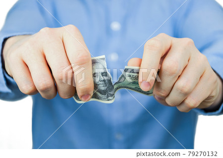 Concept of waiver of us dollars. A man in a blue shirt holds one hundred US dollars and tears them up. Concept of waiver of us dollars. A man in a blue shirt holds one hundred US dollars and tears them up. 79270132