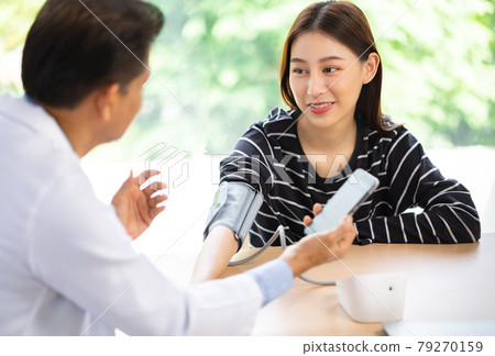 Senior doctor using sphygmomanometer with stethoscope checking blood pressure to a patient in the hospital. 79270159