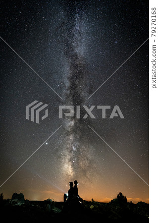 Milky way and two people silhouette with beam light Milky way and two people silhouette with beam light 79270168