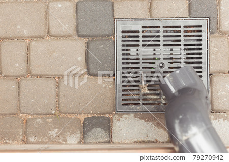 stormwater pipe on facade with rainwater drainage into the drainage system with a sewer manhole grill stormwater pipe on facade with rainwater drainage into the drainage system with a sewer manhole grill 79270942