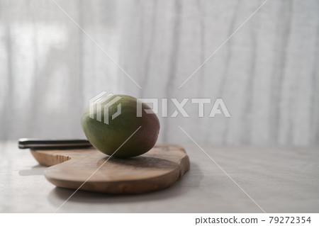 Ripe green mango on olive wood board Ripe green mango on olive wood board 79272354