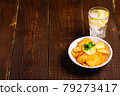 Fresh ice cold water drink with lemon near to fried potato chips with parsley leaf in wooden bowl on wood backdrop, angle view copy space 79273417