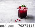 Fresh ice cold fruit cocktail in glass, refreshing summer red currant berry drink with rosemary leaf on stone concrete background, angle view copy space 79273418
