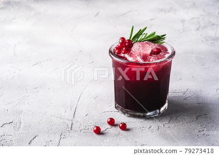 Fresh ice cold fruit cocktail in glass, refreshing summer red currant berry drink with rosemary leaf on stone concrete background, angle view copy space 79273418