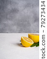 Two lemon slices, tropical citrus fruits with green leaves on white concrete background, angle view copy space 79273434