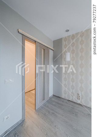 Sliding door in finishing apartment interior. Empty room in new building with repair, walls with wallpapers. Repair works on construction site of residential apartment. Sliding door in finishing apartment interior. Empty room in new building with repair, walls with wallpapers. Repair works on construction site of residential apartment. 79277237