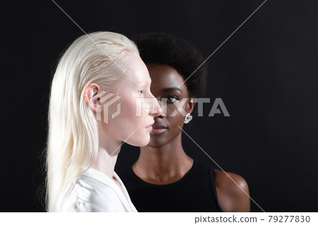 Caucasian and african american young woman isolated on black background. Caucasian and african american young woman isolated on black background. 79277830